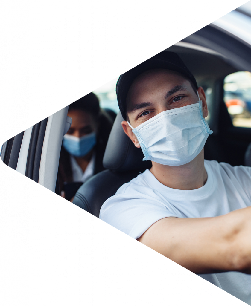 Man driving a car wearing a surgical mask