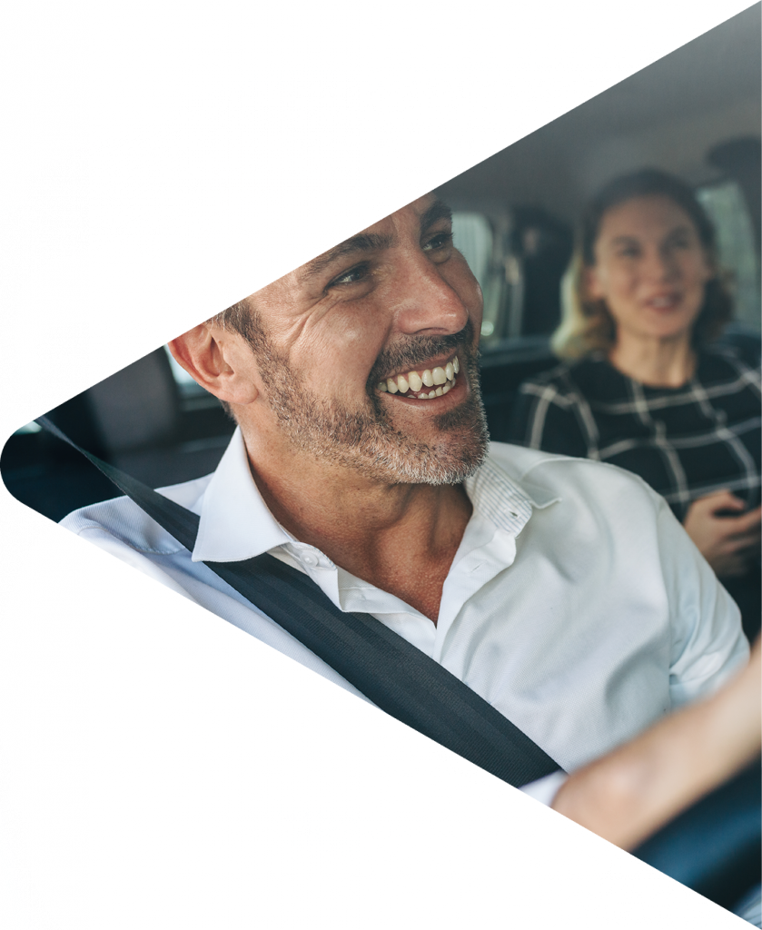 Man driving and smiling at back seat passenger