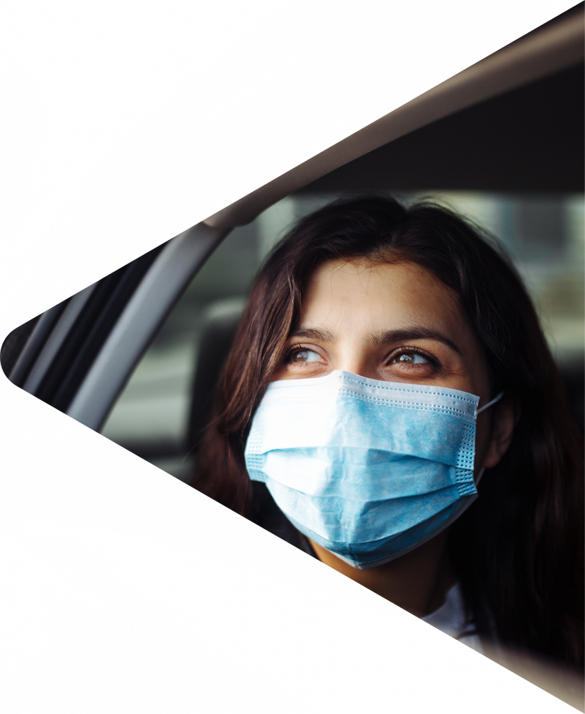 Woman in the back of a car wearing a surgical mask